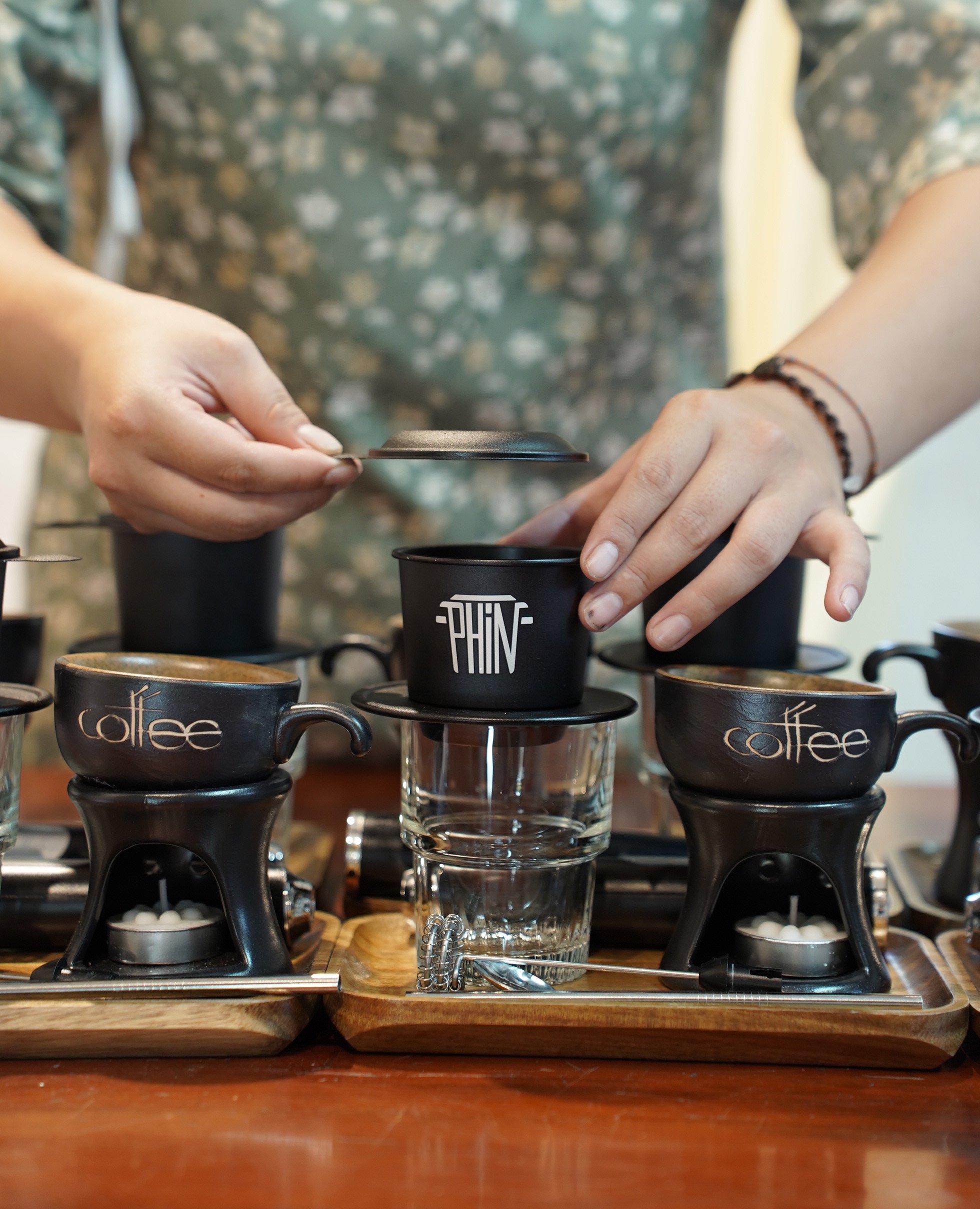Hands preparing coffee with a Vietnamese phin filter.