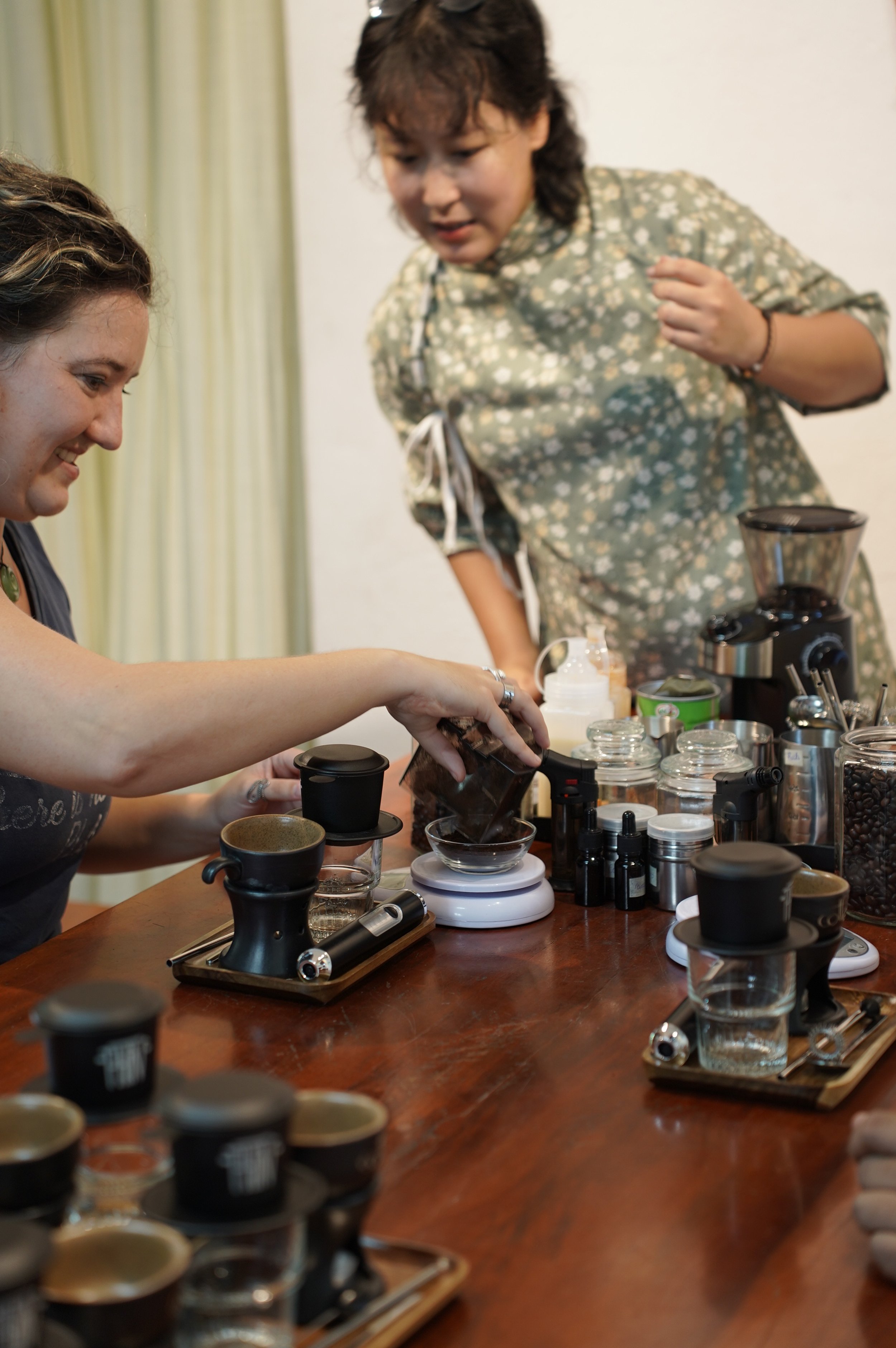 An instructor guiding a guest through Vietnamese coffee preparation.