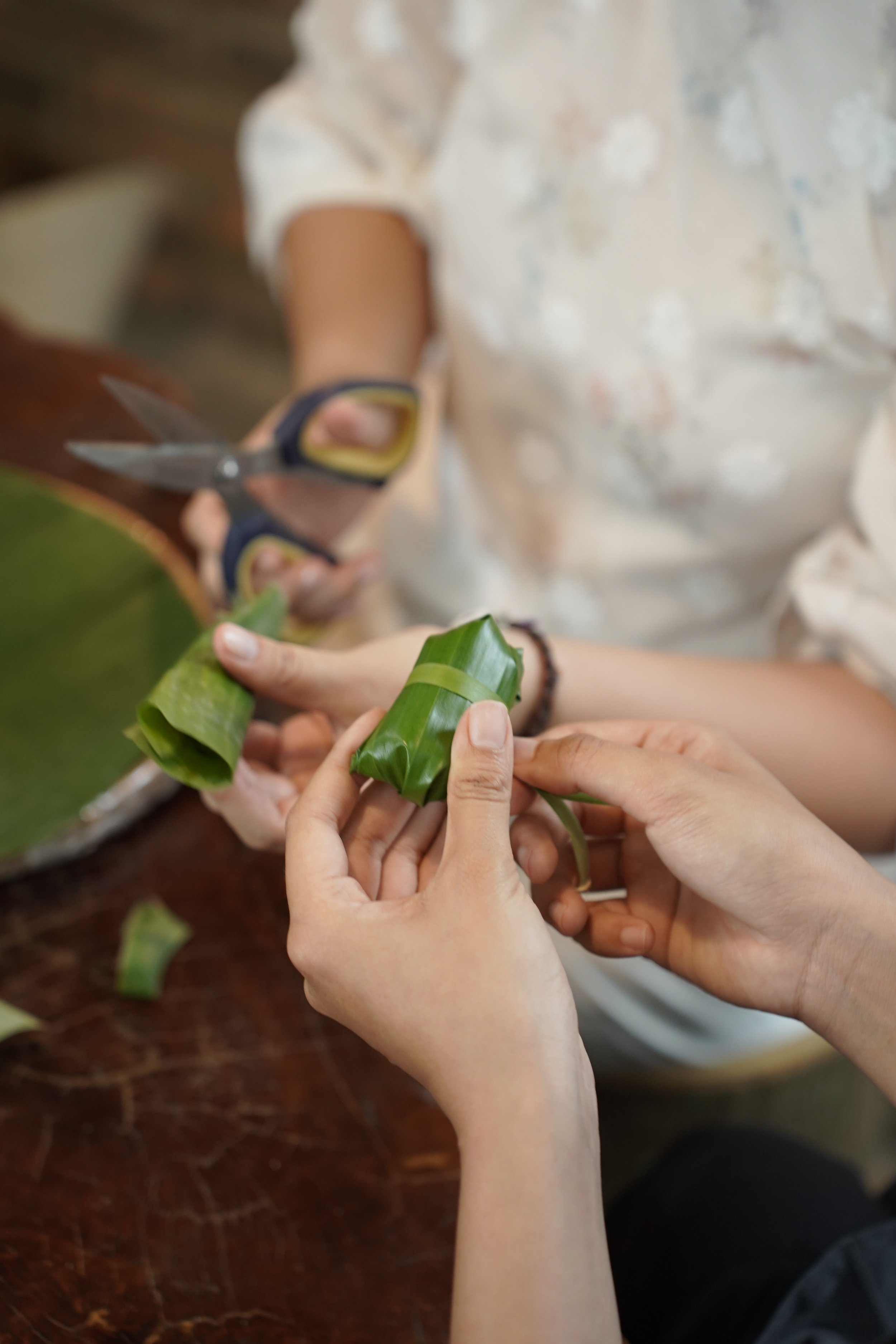 Guests wrapping dumplings in banana leaves.
